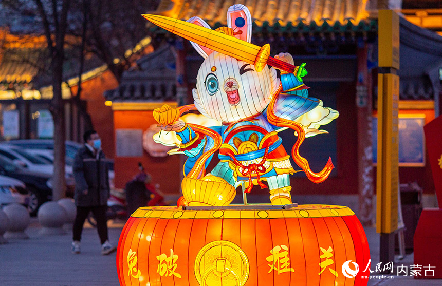 1月18日晚，游客從呼和浩特市玉泉區(qū)塞上老街歷史文化街區(qū)“兔破難關”花燈旁經(jīng)過。丁根厚攝