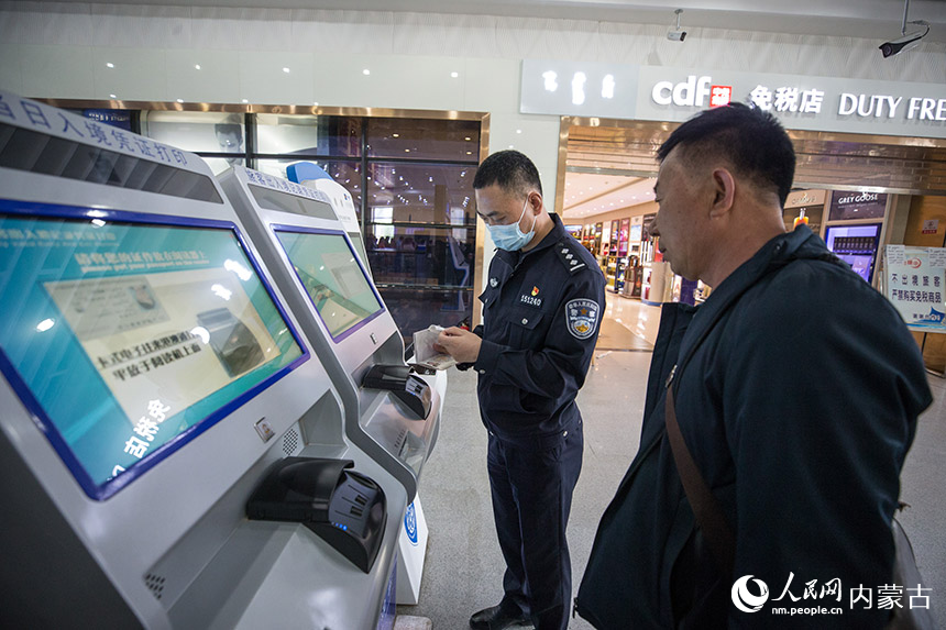 二連出入境邊防檢查站執(zhí)勤民警為旅客打印通關(guān)記錄憑證。胡富國(guó)攝