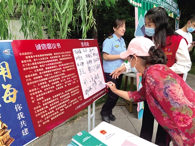 市民在誠(chéng)信倡議書上簽字。黃建飛 攝