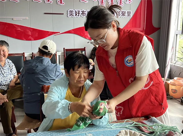 伊金霍洛鎮(zhèn)青年志愿者和老年人一起制作艾草錘。