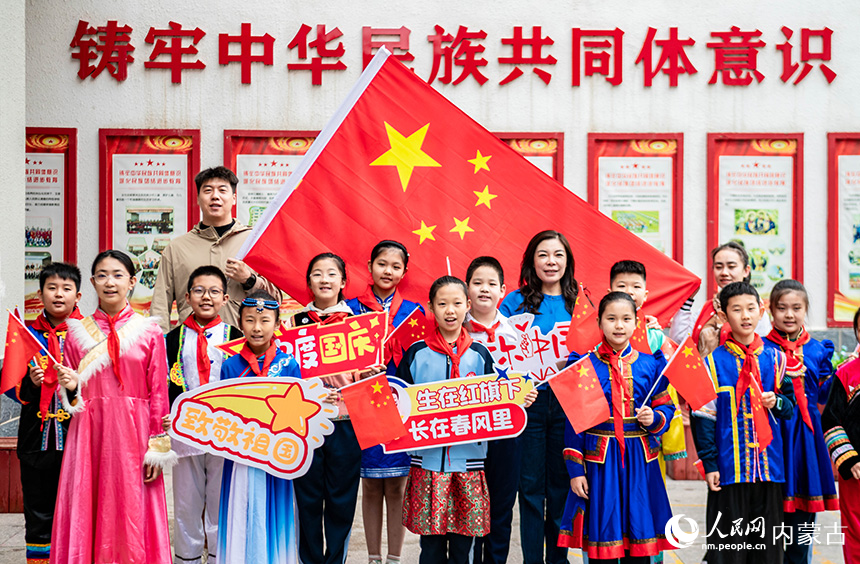 呼和浩特市玉泉區(qū)南柴火市街小學(xué)師生在“童心頌祖國 歡歌迎國慶”主題活動現(xiàn)場與國旗同框留影。丁根厚攝