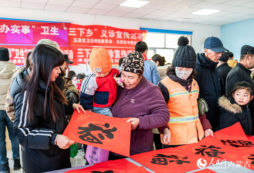 1月18日，志愿者在呼和浩特市玉泉區(qū)“三下鄉(xiāng)”活動現(xiàn)場為群眾贈送新春福字、春聯(lián)。丁根厚攝
