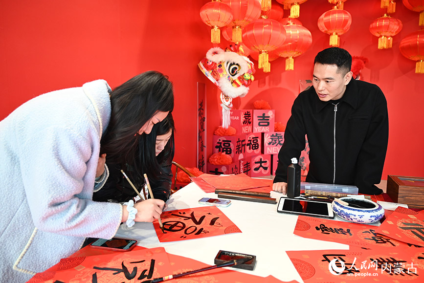 呼和浩特雕塑藝術(shù)館新春市集內(nèi)，市民在專業(yè)老師的指導(dǎo)下寫“?！弊?。人民網(wǎng)記者 劉藝琳攝